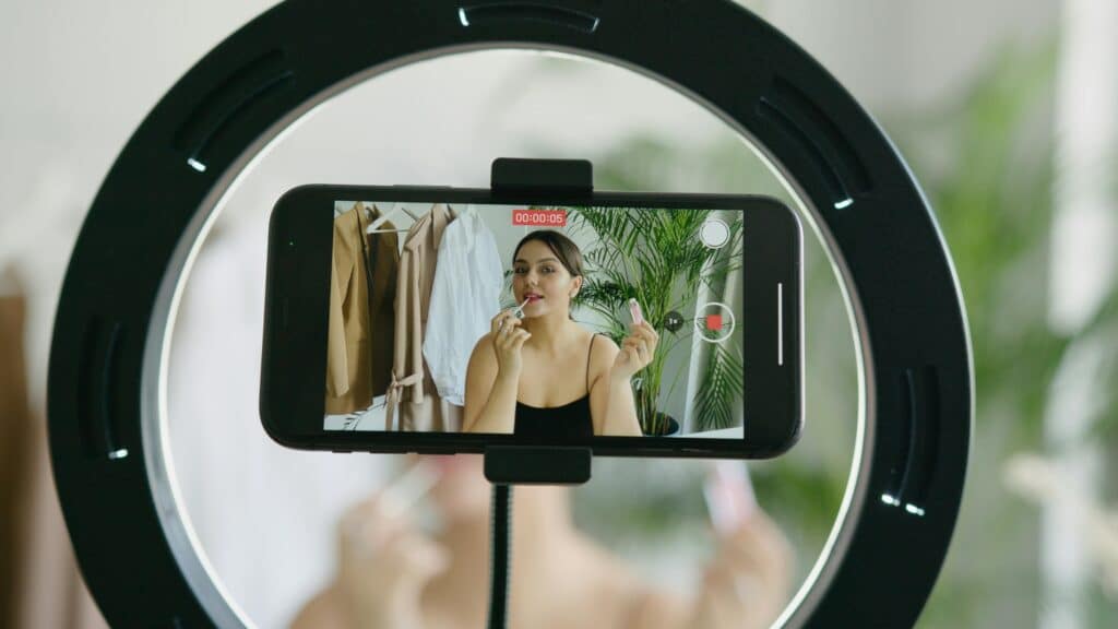 Ein Urheber nimmt ein Video mit Smartphone und Ringlicht auf; Bild auf digitaler Kommunikation